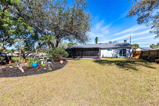 rear view of property featuring a sunroom, fence, and a lawn