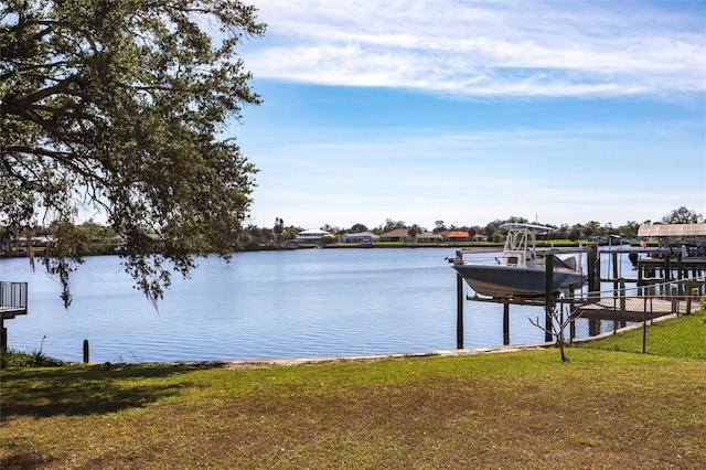 dock area featuring a water view, boat lift, and a lawn