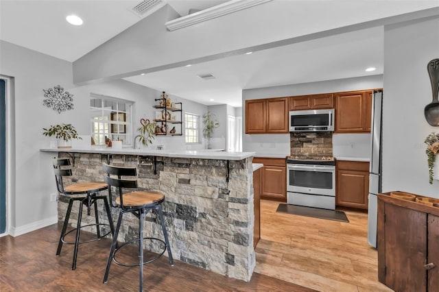 kitchen featuring a peninsula, a kitchen bar, stainless steel appliances, and light countertops