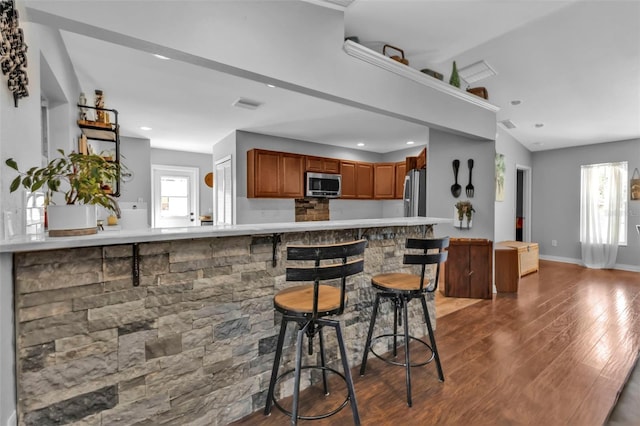 kitchen featuring brown cabinets, stainless steel appliances, visible vents, light countertops, and a peninsula