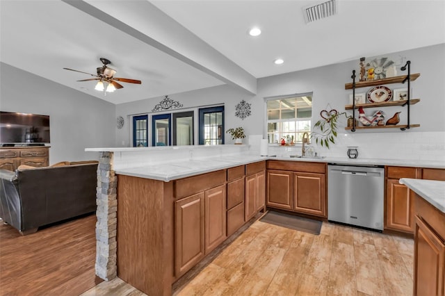 kitchen featuring visible vents, brown cabinetry, a peninsula, light wood-style floors, and stainless steel dishwasher