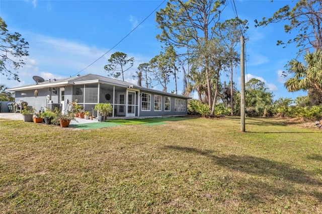 rear view of house featuring a sunroom and a yard