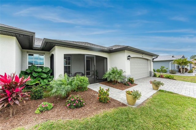 exterior space featuring a garage, decorative driveway, a front yard, and stucco siding