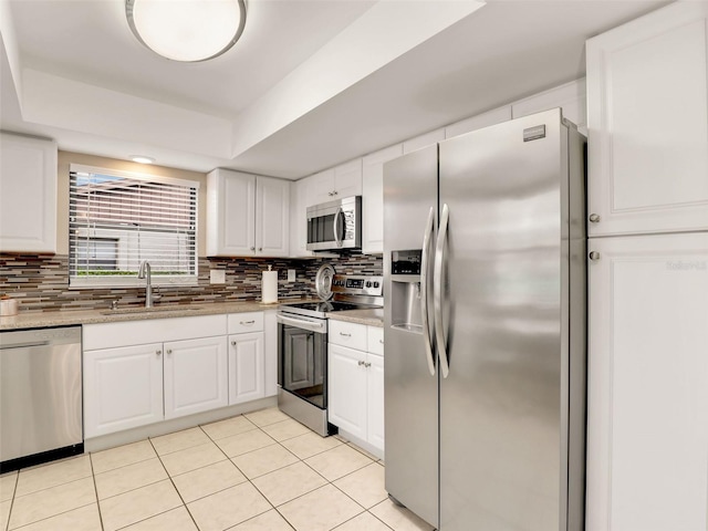 kitchen featuring appliances with stainless steel finishes, white cabinetry, a sink, and backsplash