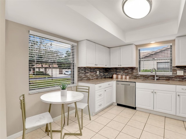 kitchen with tasteful backsplash, white cabinets, dishwasher, and a sink