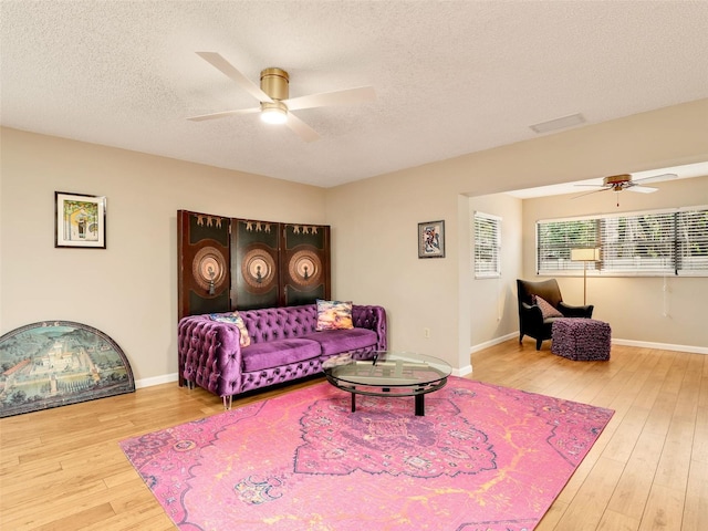 living room with a textured ceiling, baseboards, and wood finished floors