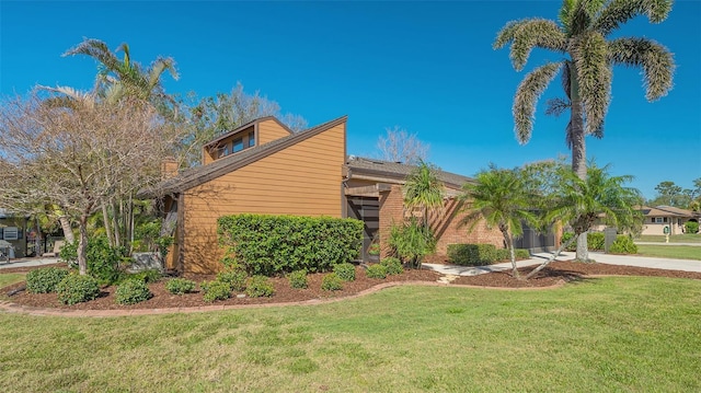 view of home's exterior with a chimney, a lawn, and brick siding