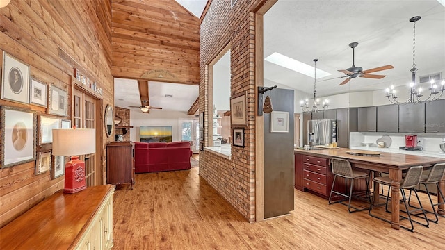 kitchen with stainless steel refrigerator with ice dispenser, light wood finished floors, visible vents, open floor plan, and a kitchen breakfast bar