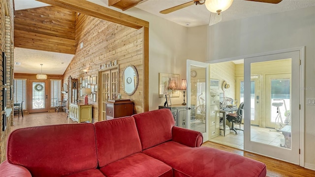 living area featuring french doors, a ceiling fan, a textured ceiling, high vaulted ceiling, and light wood-type flooring