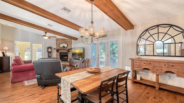 dining space with a brick fireplace, wood finished floors, visible vents, and a healthy amount of sunlight