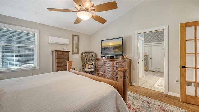 bedroom featuring lofted ceiling, light wood-style flooring, an AC wall unit, ceiling fan, and a textured ceiling