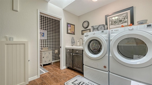 washroom featuring wood finished floors, a sink, baseboards, independent washer and dryer, and cabinet space