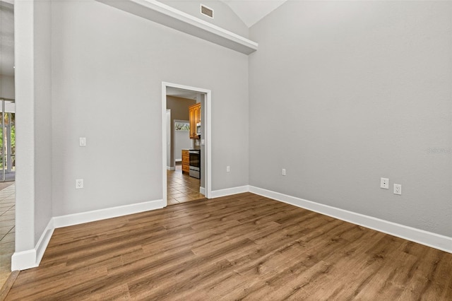 spare room with high vaulted ceiling and hardwood / wood-style flooring