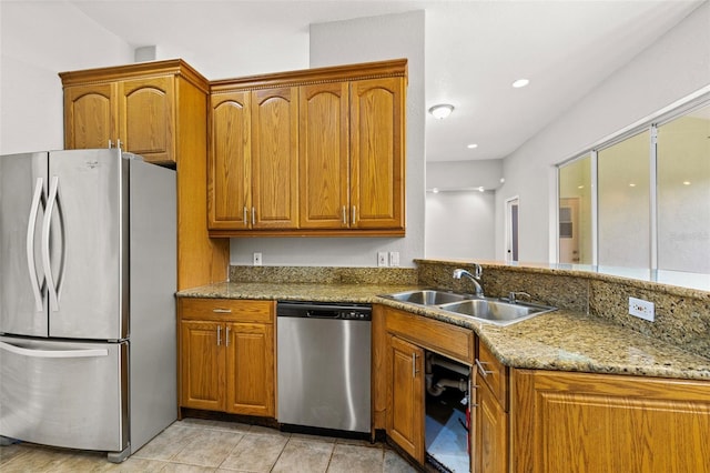 kitchen featuring appliances with stainless steel finishes, light tile patterned floors, sink, and light stone countertops