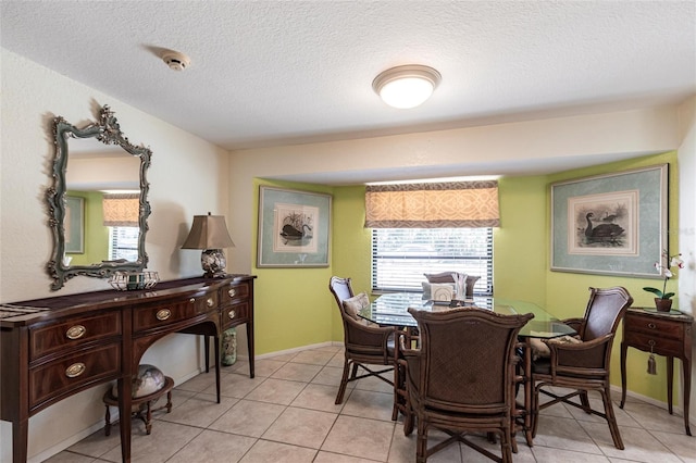 dining space featuring a textured ceiling, baseboards, and light tile patterned floors