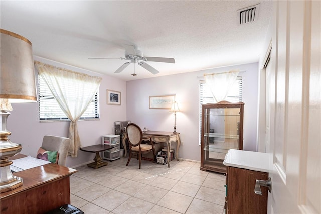 home office featuring visible vents, a ceiling fan, light tile patterned flooring, a textured ceiling, and baseboards