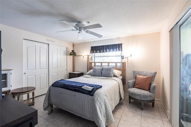bedroom with a ceiling fan, a closet, a textured ceiling, and light tile patterned floors