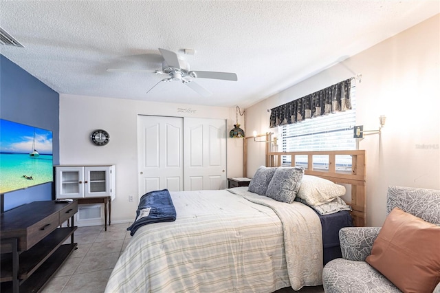 bedroom featuring light tile patterned floors, ceiling fan, a textured ceiling, visible vents, and a closet
