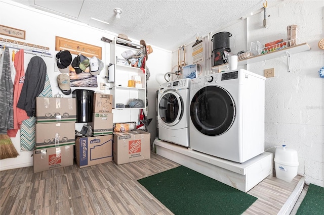 laundry room featuring washing machine and dryer, laundry area, a textured ceiling, and wood finished floors