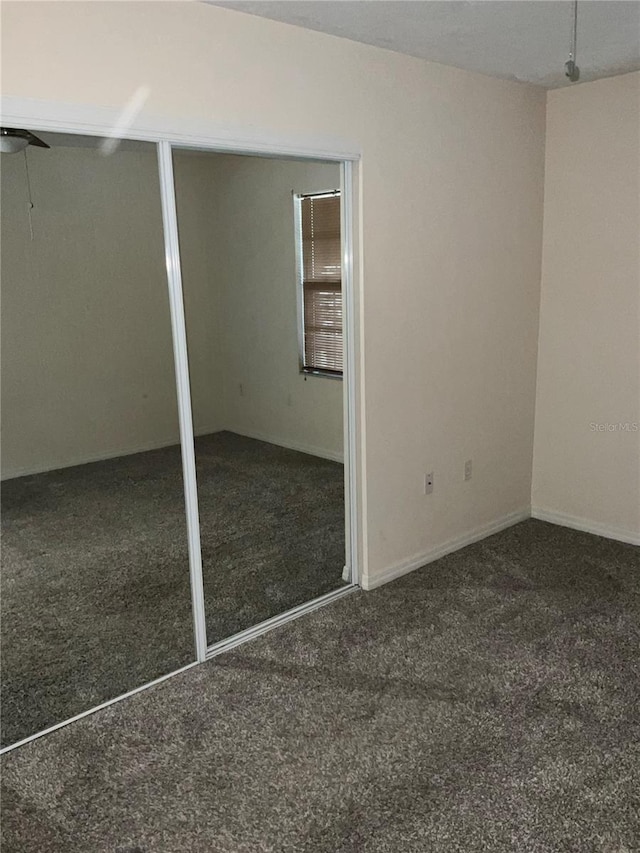 unfurnished bedroom with dark carpet and multiple closets