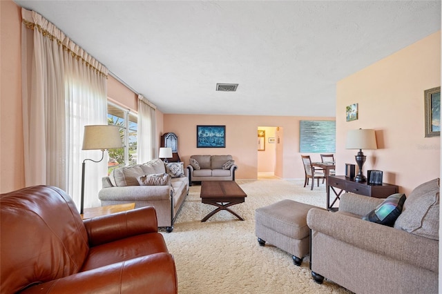 living room featuring light carpet, a textured ceiling, and visible vents