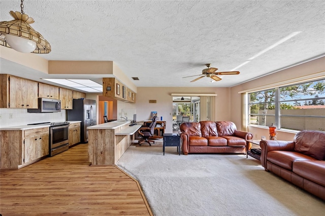 living area featuring ceiling fan, light wood-style flooring, visible vents, and a wealth of natural light