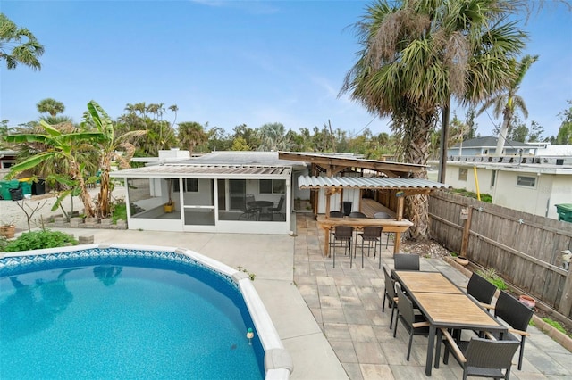 view of pool featuring a patio, an outdoor bar, and a sunroom