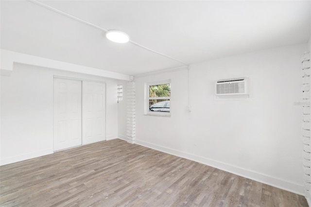23475 Harper Ave, Port Charlotte, FL 33980 - unfurnished bedroom featuring wood finished floors, baseboards, a closet, and a wall unit AC