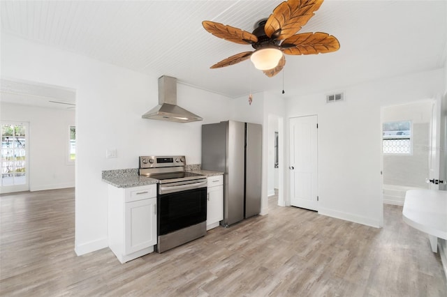 23475 Harper Ave, Port Charlotte, FL 33980 - kitchen featuring wall chimney exhaust hood, stainless steel appliances, light wood-style flooring, white cabinets, and ceiling fan