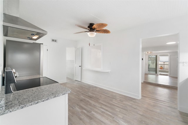 23475 Harper Ave, Port Charlotte, FL 33980 - kitchen featuring range, ceiling fan, light wood-style flooring, wall chimney exhaust hood, and light stone counters