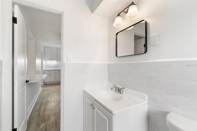 23475 Harper Ave, Port Charlotte, FL 33980 - half bath featuring tile walls, vanity, toilet, wood finished floors, and wainscoting