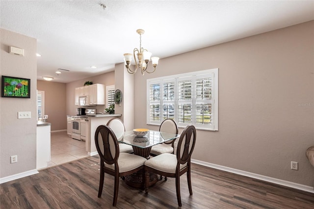 dining area with baseboards, recessed lighting, light wood-type flooring, and a notable chandelier