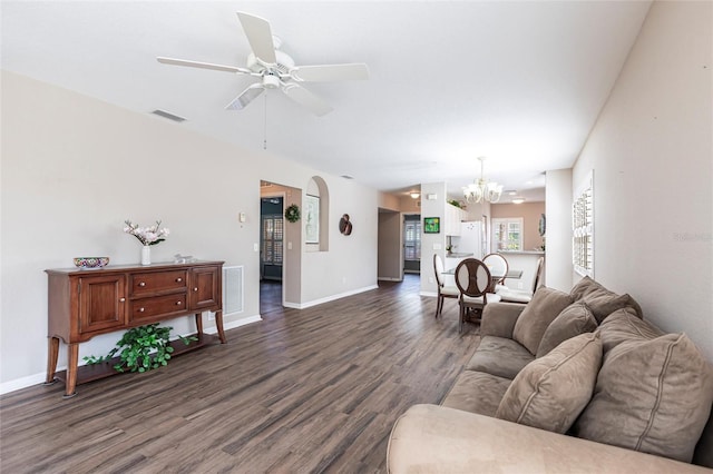 living area with dark wood-style floors, ceiling fan with notable chandelier, visible vents, and baseboards