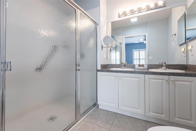 bathroom featuring double vanity, a stall shower, a sink, and tile patterned floors