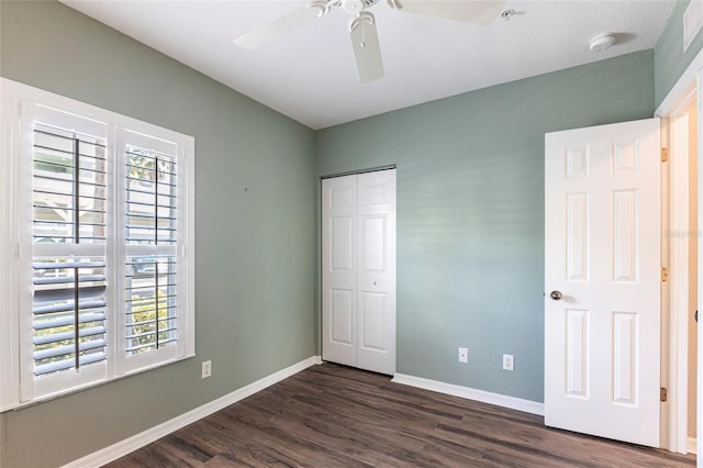 unfurnished bedroom featuring dark wood-style floors, ceiling fan, a closet, and baseboards