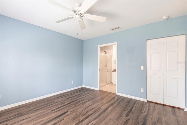 unfurnished bedroom featuring baseboards, visible vents, dark wood-style floors, ceiling fan, and a closet