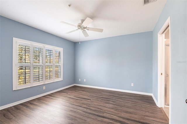 empty room with dark wood-style floors, ceiling fan, visible vents, and baseboards