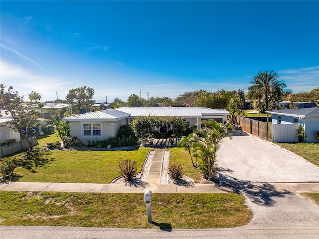 view of front of property with metal roof, driveway, a front lawn, and fence