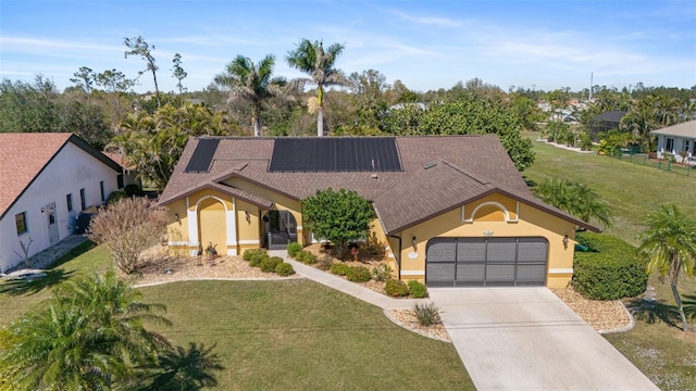 view of front of home featuring stucco siding, solar panels, concrete driveway, and a front yard