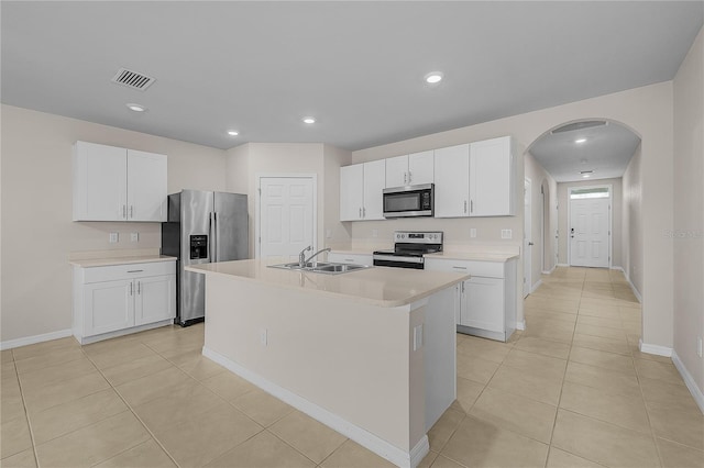 kitchen with arched walkways, stainless steel appliances, light countertops, visible vents, and a sink