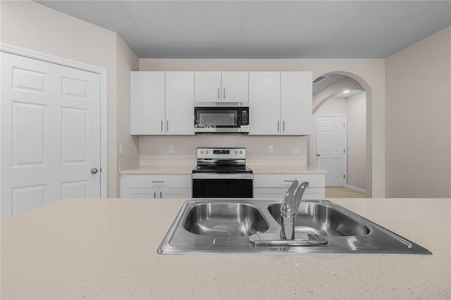 kitchen featuring stainless steel appliances, light countertops, a sink, and white cabinetry