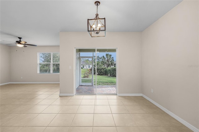 spare room with ceiling fan with notable chandelier, baseboards, and light tile patterned flooring