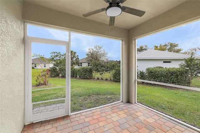 unfurnished sunroom featuring a ceiling fan and a healthy amount of sunlight