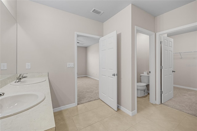 bathroom featuring toilet, a sink, visible vents, and tile patterned floors