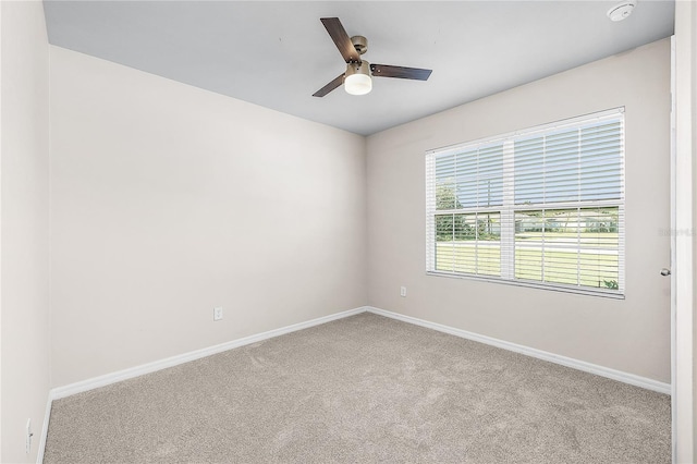 carpeted spare room with ceiling fan and baseboards