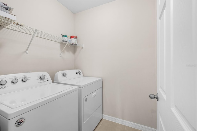 clothes washing area featuring light tile patterned floors, laundry area, independent washer and dryer, and baseboards