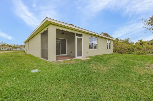 back of property featuring a lawn, a sunroom, and stucco siding