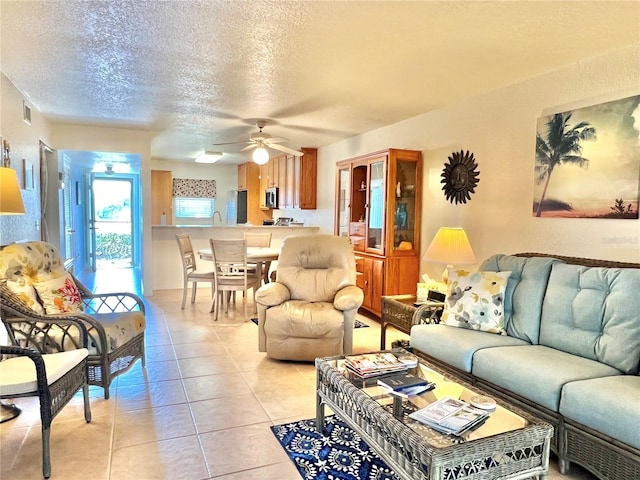 living area featuring a textured ceiling, light tile patterned flooring, visible vents, and a ceiling fan