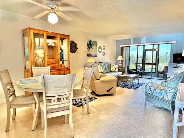 dining space featuring light tile patterned floors, a ceiling fan, and a textured ceiling