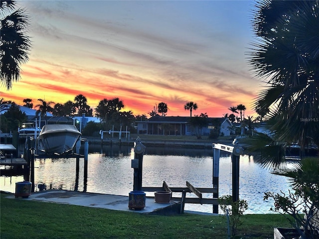 dock area with a water view, boat lift, and a lawn